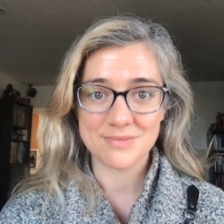 Woman with glasses and long hair looking at the camera